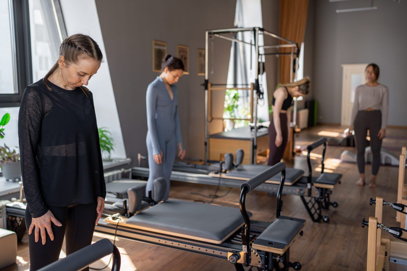 Studio de Pilates avec plusieurs Reformers et pratiquantes debout